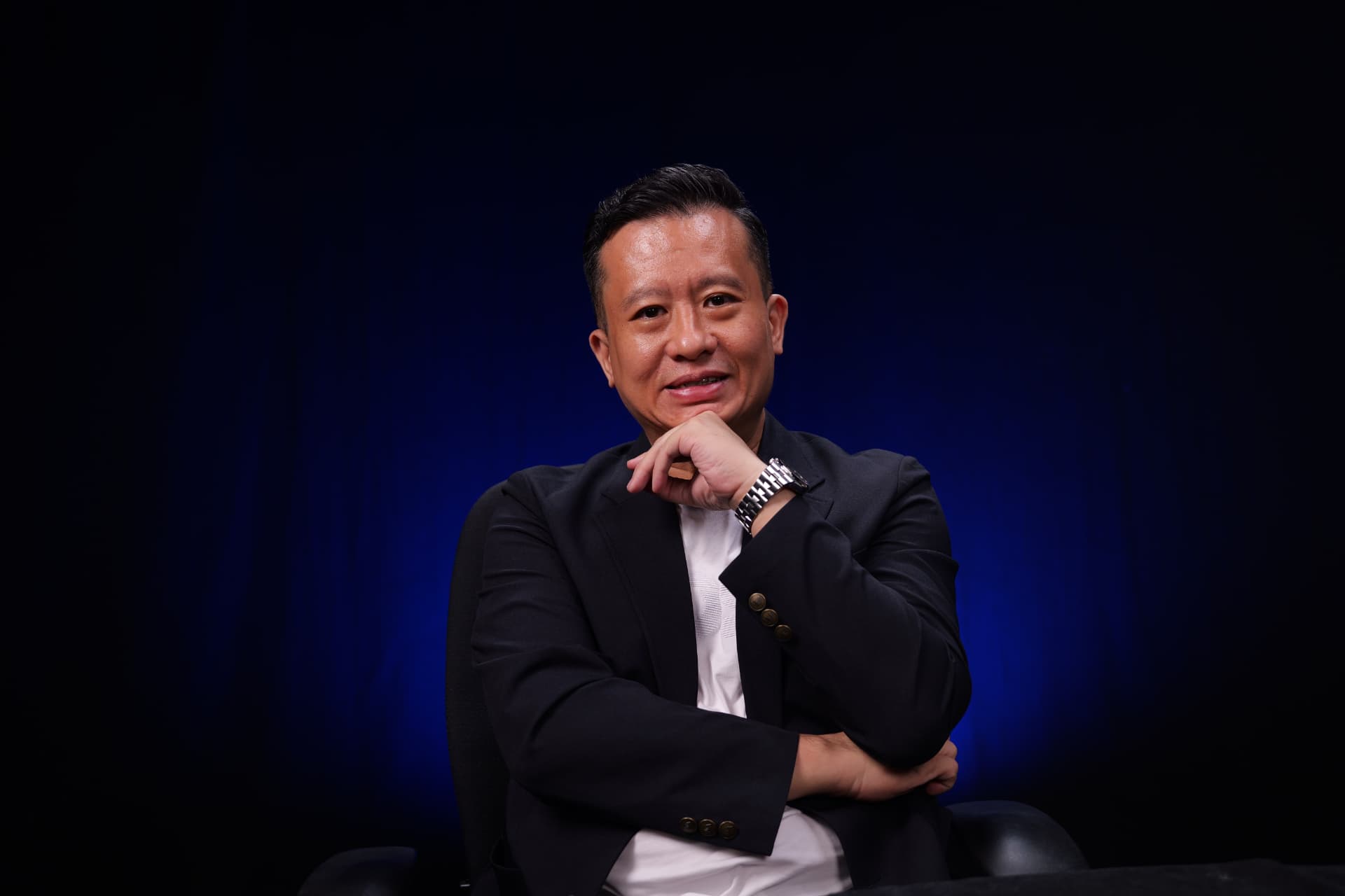 MC Gan in conversation, hand resting at his chin